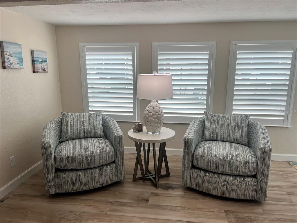 Two patterned armchairs flank a small round table with a lamp in a bright room — 6154 MIDNIGHT PASS ROAD UNIT D16, SARASOTA, FL