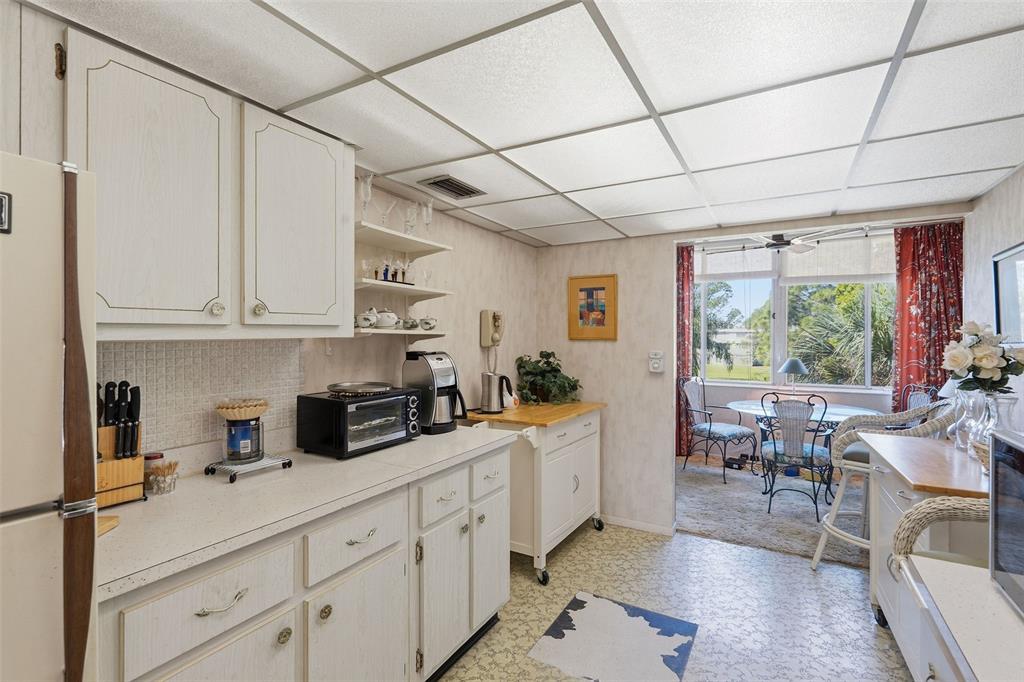 A kitchen with white cabinets, a drop ceiling, and an adjacent dining area with windows — 4890 BAY STREET NE UNIT 326, ST PETERSBURG, FL