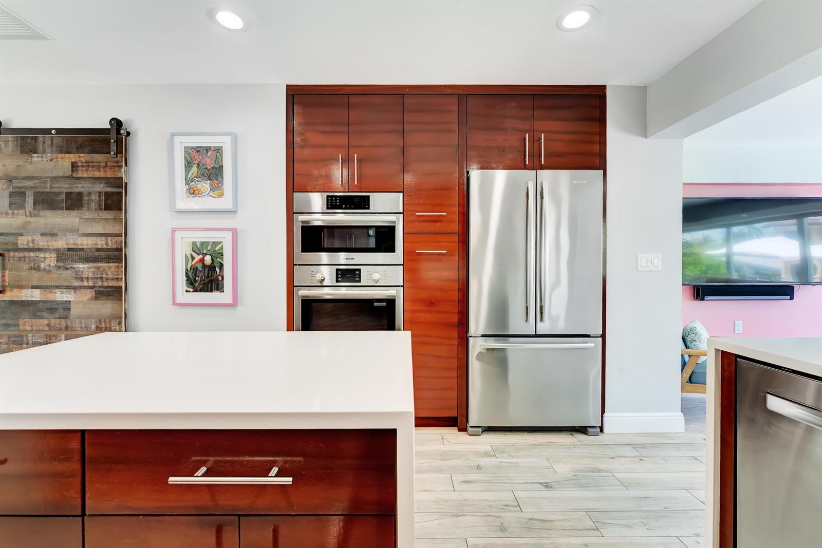 A kitchen features dark wood cabinetry, stainless steel appliances, and a white island countertop — 2291 SE 15th Street, Pompano Beach FL 33062, POMPANO BEACH, FL