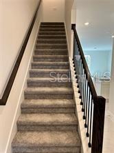 A carpeted staircase features dark wooden handrails and black metal balusters — 1130 DESERT CANDLE, OCOEE, FL