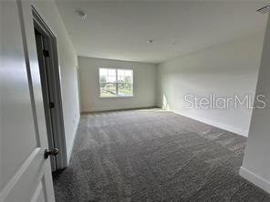 An empty bedroom with gray carpet, white walls, and a window overlooking a grassy area — 1130 DESERT CANDLE, OCOEE, FL