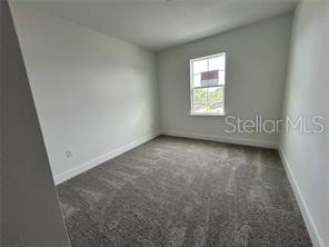 An empty bedroom features gray carpet, white walls, and a single window — 1130 DESERT CANDLE, OCOEE, FL