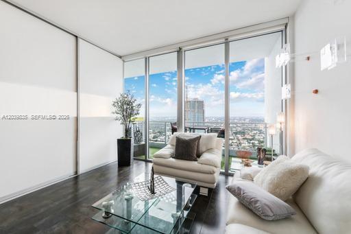 A modern living room features dark wood floors, a white sofa, and floor-to-ceiling windows — 92 SW 3rd St # 5108, Miami FL 33130, MIAMI, FL