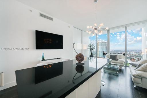 A modern living room features a black kitchen island, a wall-mounted television, and floor-to-ceiling windows — 92 SW 3rd St # 5108, Miami FL 33130, MIAMI, FL