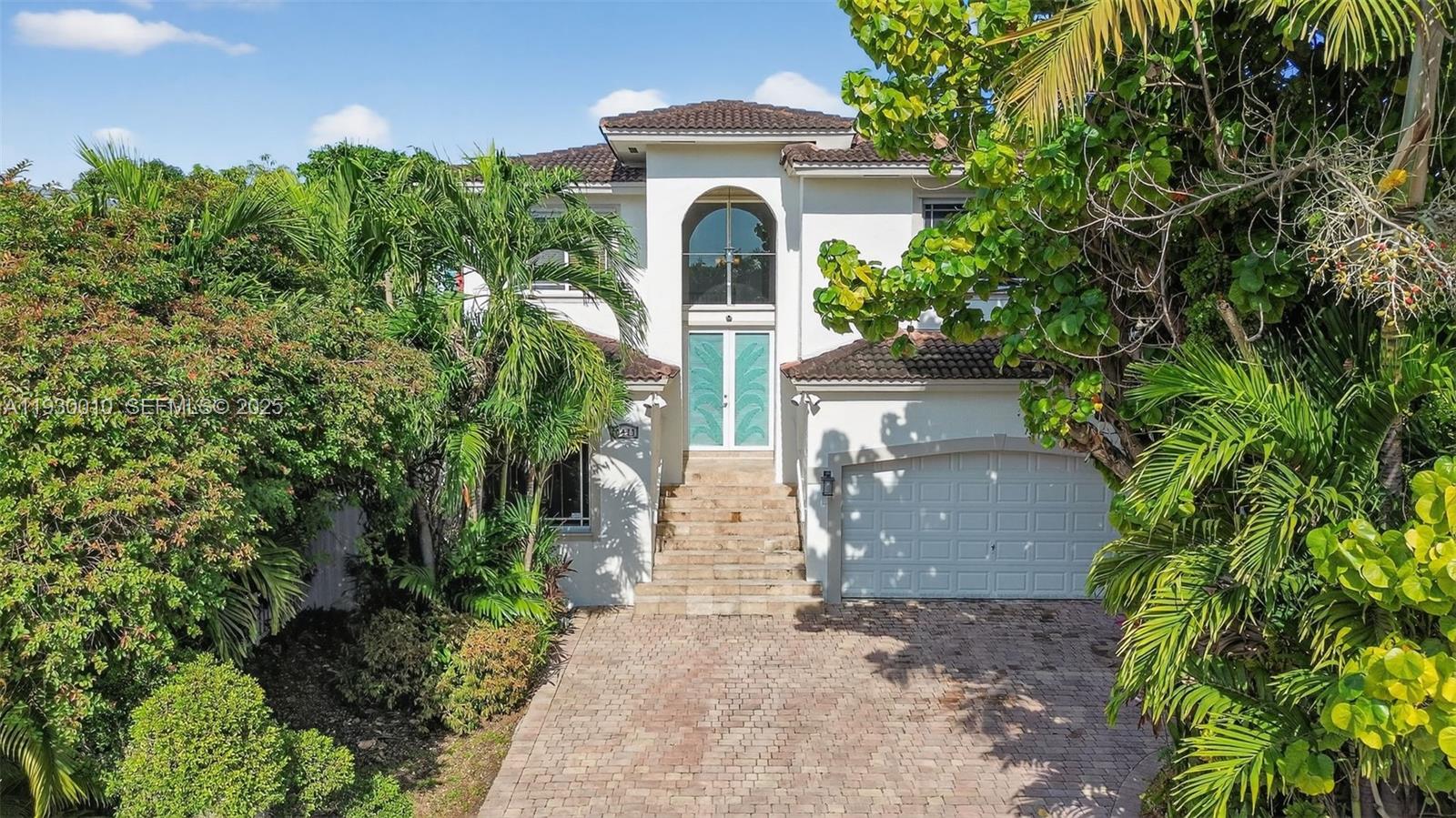 A paved driveway leads toward a lush, tropical garden area next to a house exterior — 2913 SW 13th St, Miami FL 33145, MIAMI, FL