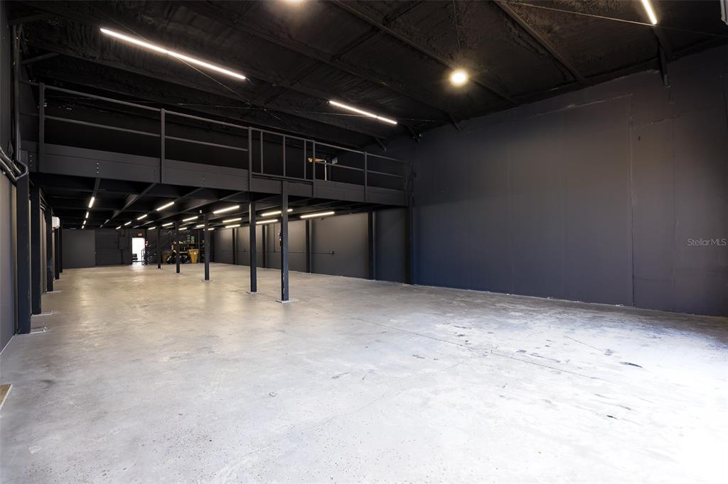 A large, empty industrial warehouse space features a black ceiling, concrete floors, and a mezzanine — 1318 SPRUCE AVENUE UNIT 1345b, ORLANDO, FL