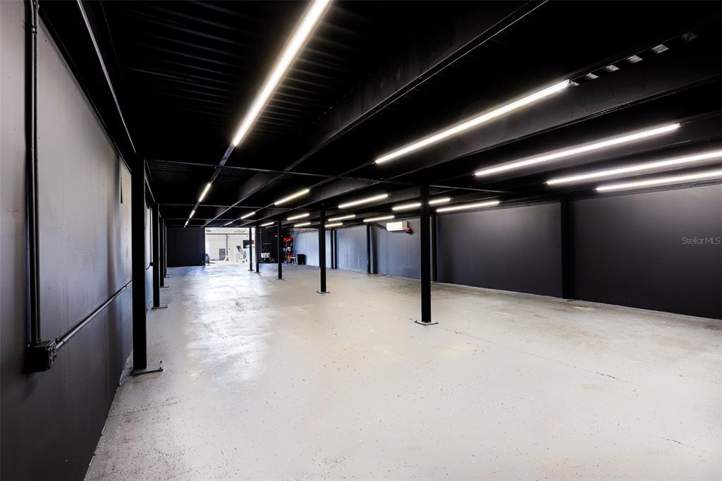 An empty industrial-style space features black walls, exposed ceiling beams, and overhead fluorescent lighting — 1318 SPRUCE AVENUE UNIT 1345b, ORLANDO, FL