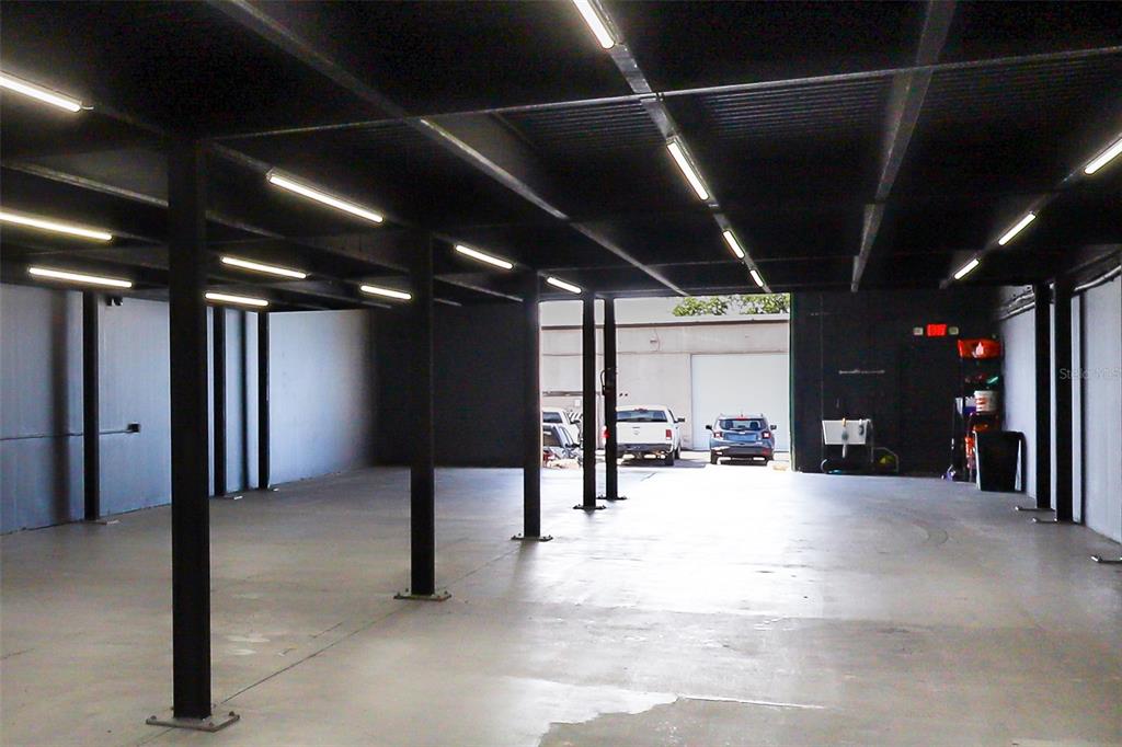 An open, industrial-style warehouse space with a concrete floor, dark ceiling, and overhead lighting — 1318 SPRUCE AVENUE UNIT 1345b, ORLANDO, FL