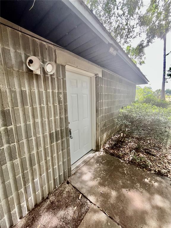 A white exterior door with a number three is set into a textured concrete block wall — 2321 SW 31ST PLACE UNIT 1, GAINESVILLE, FL