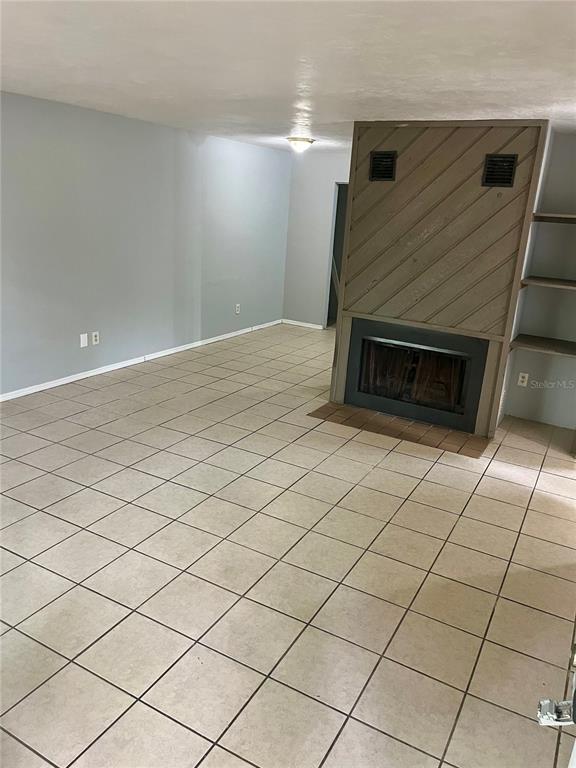 A living room features light-colored floor tiles, gray walls, and a wood-paneled fireplace — 2321 SW 31ST PLACE UNIT 1, GAINESVILLE, FL