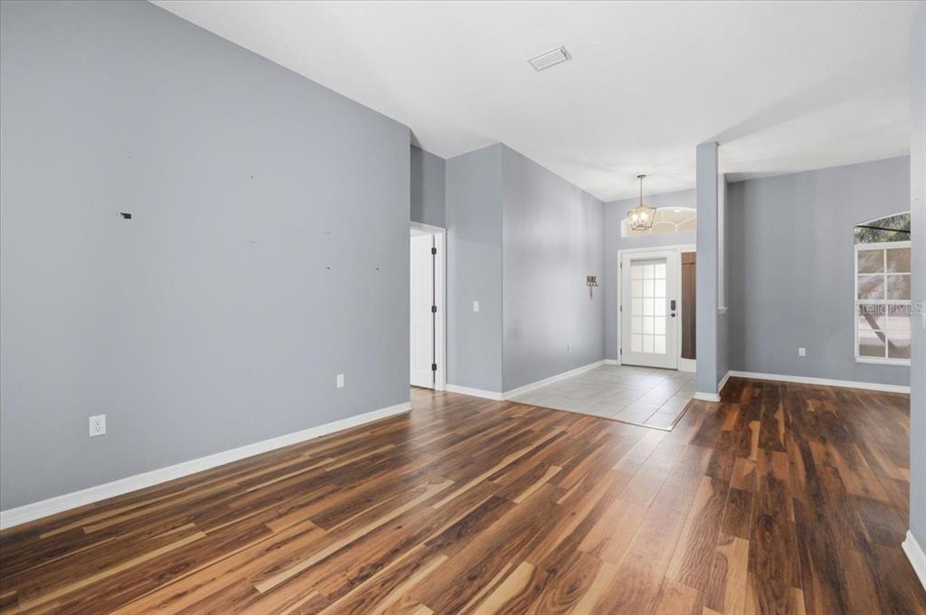 An empty room with light blue walls, wood-look flooring, and a tiled entryway — 5237 BLOOMFIELD BOULEVARD, LAKELAND, FL