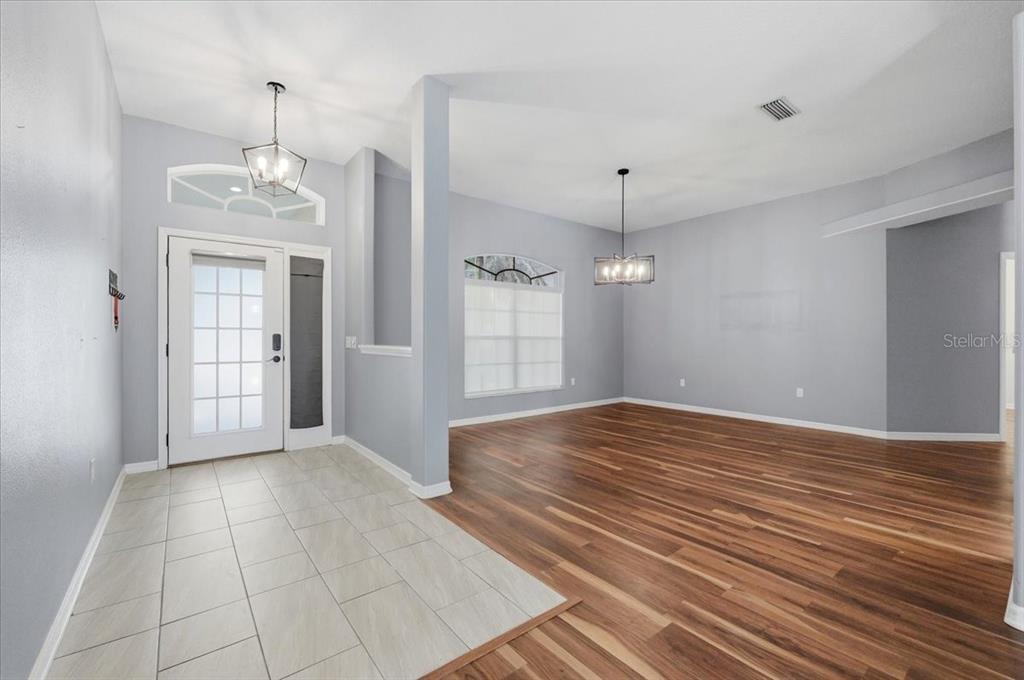 An entryway with tile flooring transitions into a living area with wood-look floors — 5237 BLOOMFIELD BOULEVARD, LAKELAND, FL