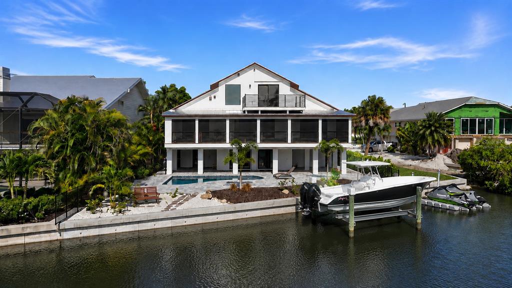 An exterior view of a waterfront house with a pool, boat lift, and dock — 2795 N BEACH ROAD UNIT B, ENGLEWOOD, FL