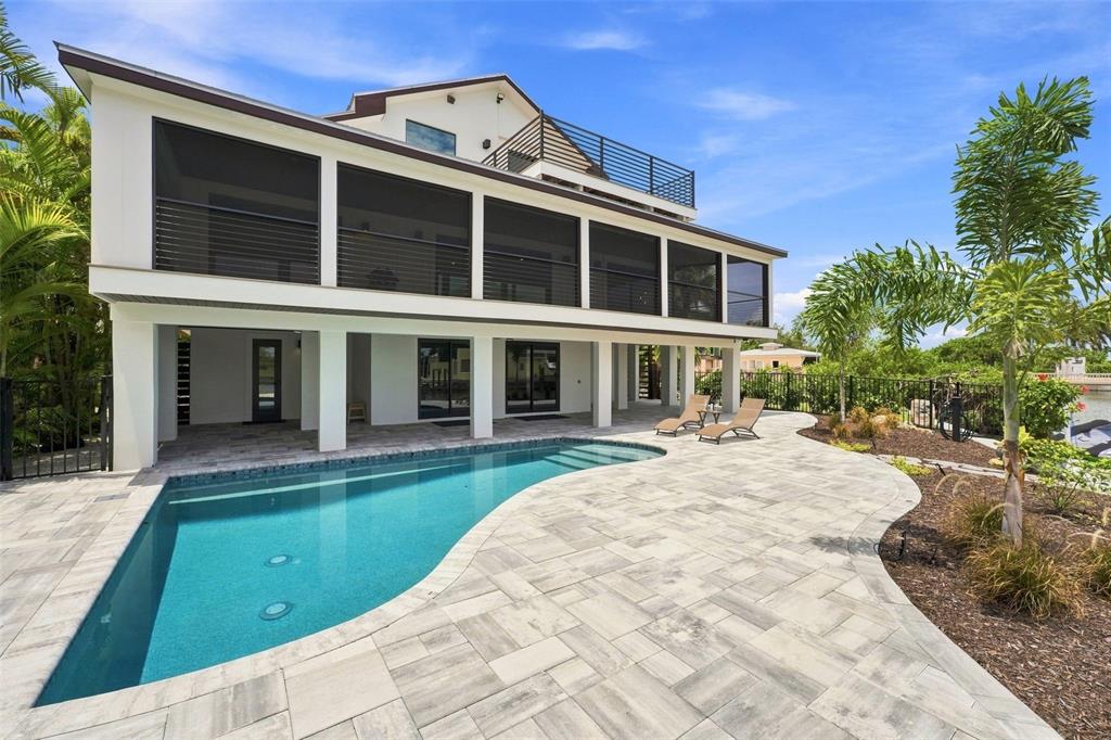 A multi-story house with a screened balcony, a swimming pool, and a paved patio area — 2795 N BEACH ROAD UNIT B, ENGLEWOOD, FL