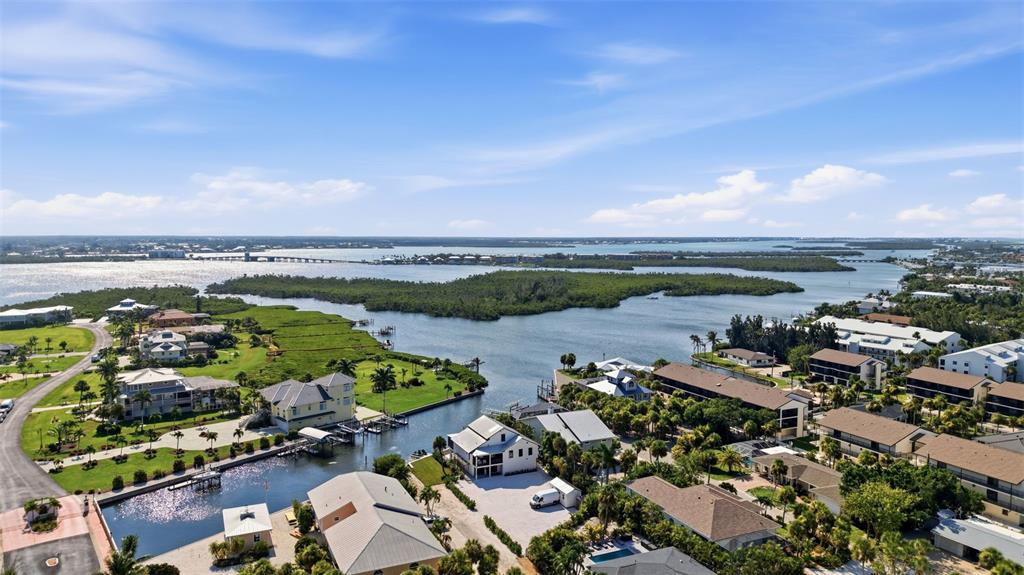 An aerial view shows waterfront homes, a canal, and a bridge over a large bay — 2795 N BEACH ROAD UNIT B, ENGLEWOOD, FL