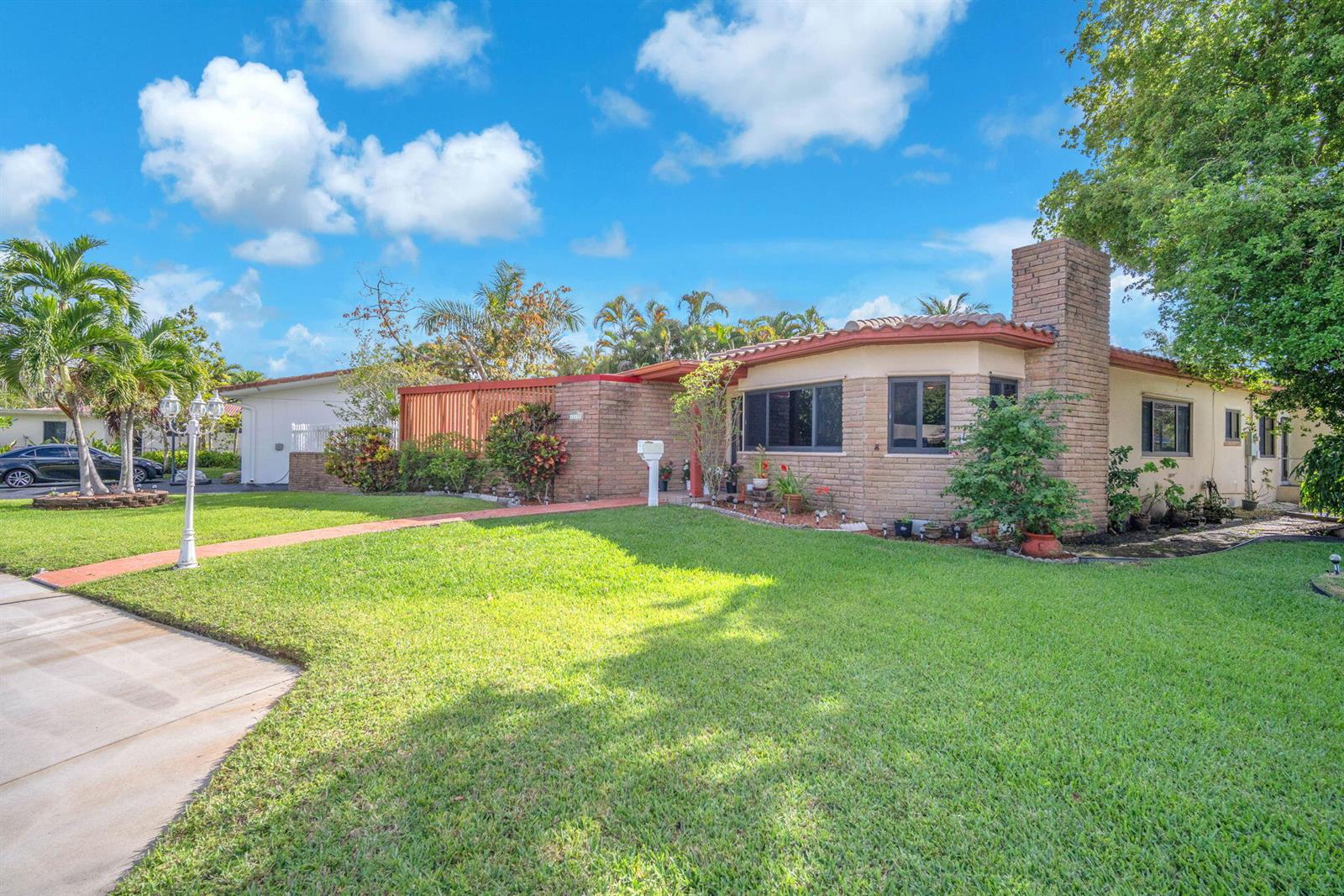 A single-story house with a brick facade, tile roof, and a large front lawn — 11490 W Biscayne Canal Road, Miami FL 33161, MIAMI, FL