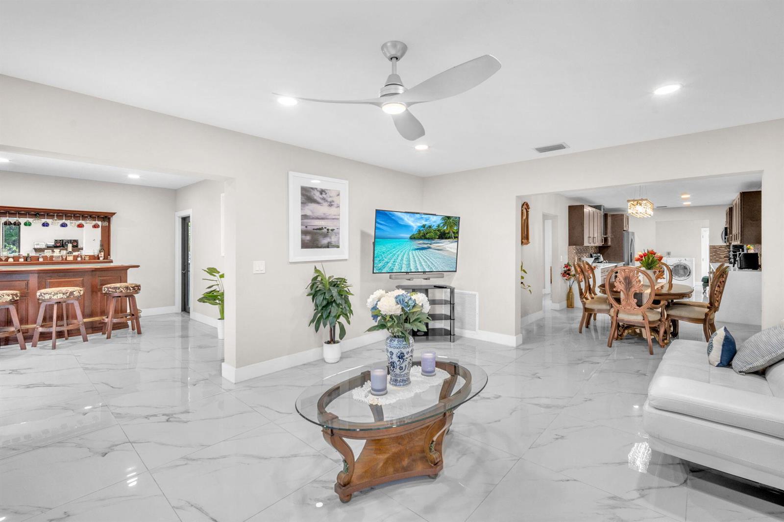 A living room with white marble floors, a glass coffee table, and a ceiling fan — 11490 W Biscayne Canal Road, Miami FL 33161, MIAMI, FL
