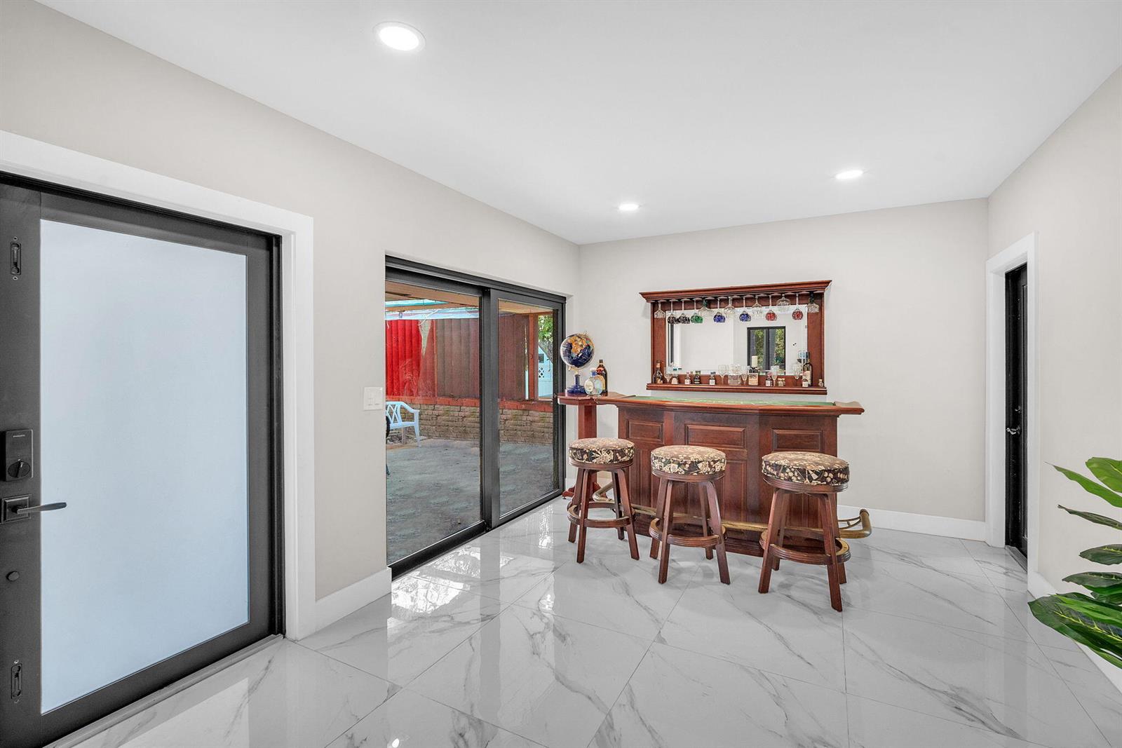 A room with white marble-look tile flooring, a home bar, and sliding glass patio doors — 11490 W Biscayne Canal Road, Miami FL 33161, MIAMI, FL