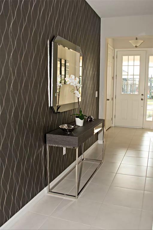 A modern entryway features a dark wavy-patterned wallpaper, a silver-framed mirror, and a console table — 1816 SANDY PARK TRAIL, KISSIMMEE, FL