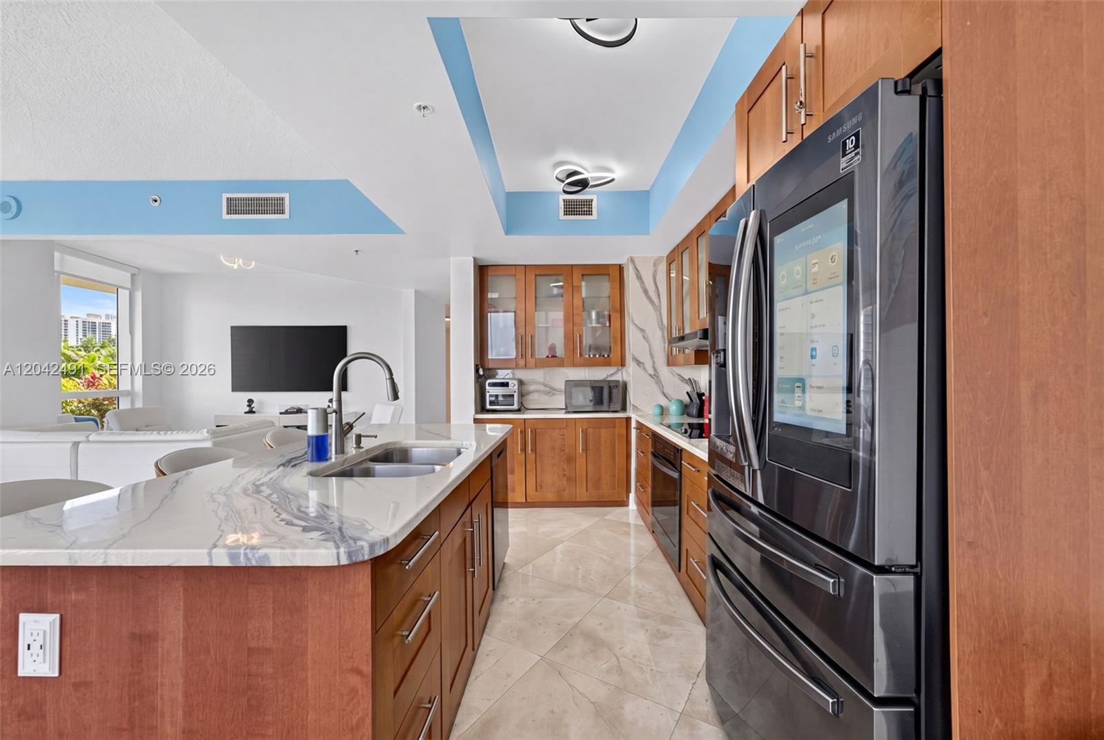 A modern kitchen features wood cabinetry, marble countertops, and a smart refrigerator — 480 NE 30th St # 1807, Miami FL 33137, MIAMI, FL