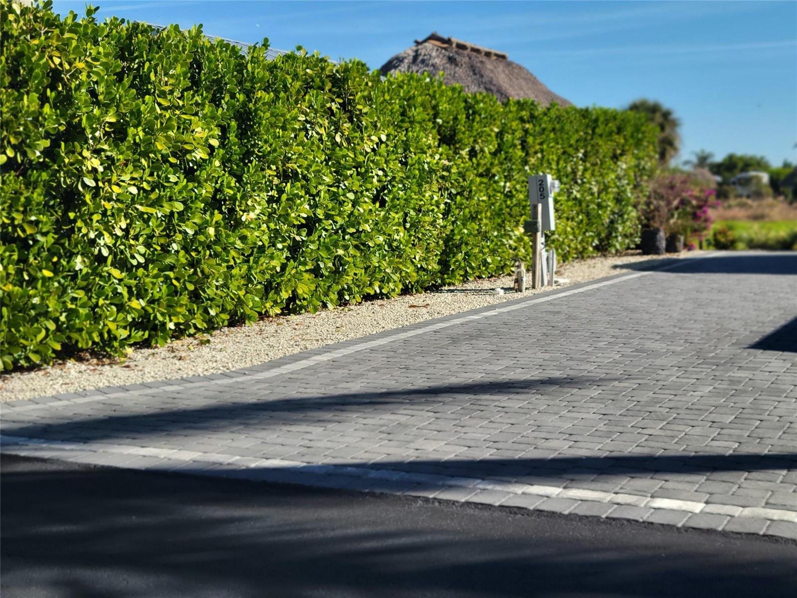 A paved driveway leads to a tall green hedge with a numbered post in the foreground — 3704 SW 7th Manor, Okeechobee FL 34974, OKEECHOBEE, FL