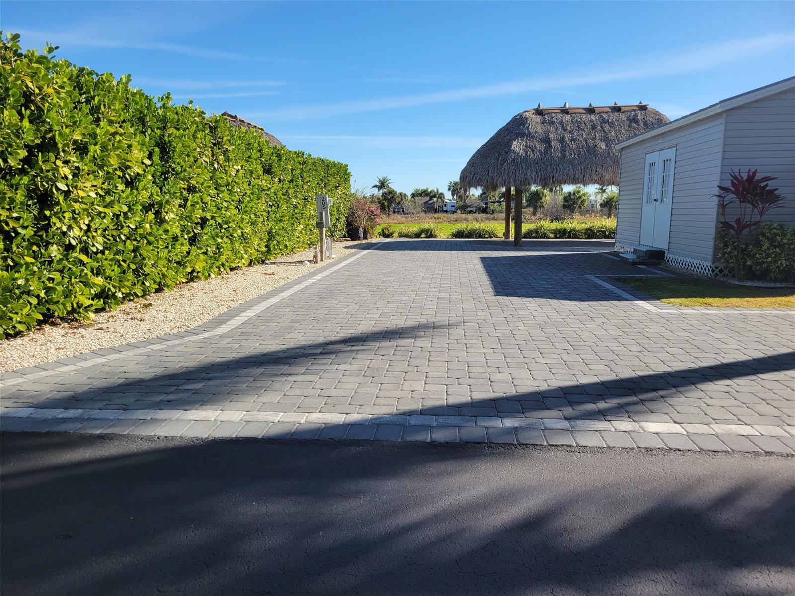 A paved driveway leads to a tiki hut and a small building beside a hedge — 3704 SW 7th Manor, Okeechobee FL 34974, OKEECHOBEE, FL