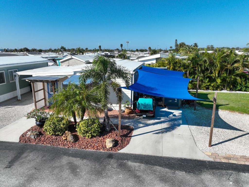 An exterior view of a mobile home featuring a blue shade sail over a driveway — 1475 FLAMINGO DRIVE UNIT 346, ENGLEWOOD, FL