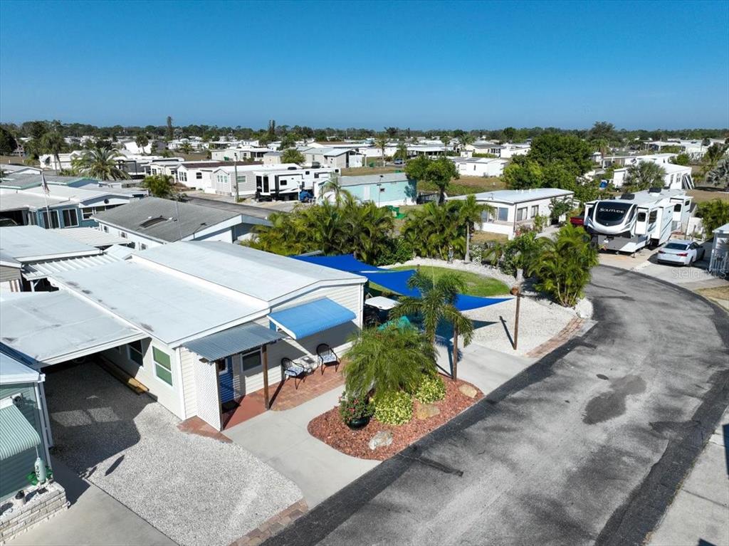An aerial view shows a manufactured home with a blue awning and patio area — 1475 FLAMINGO DRIVE UNIT 346, ENGLEWOOD, FL