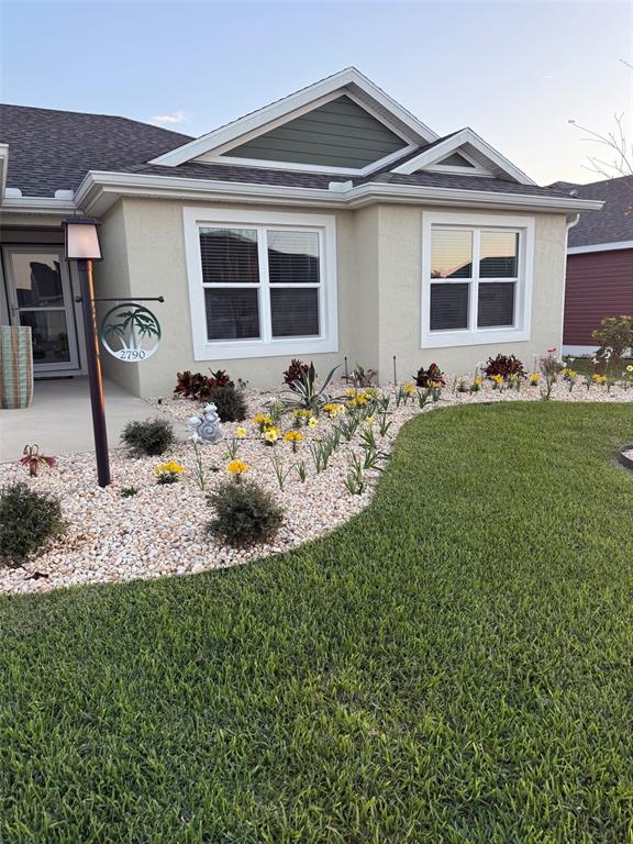 A single-story house exterior features beige stucco, a gabled roof, and a landscaped rock garden — 2790 CARYTOWN LOOP, THE VILLAGES, FL