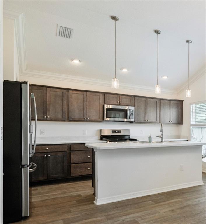 A kitchen features dark wood cabinets, stainless steel appliances, a white island, and wood flooring — 2790 CARYTOWN LOOP, THE VILLAGES, FL