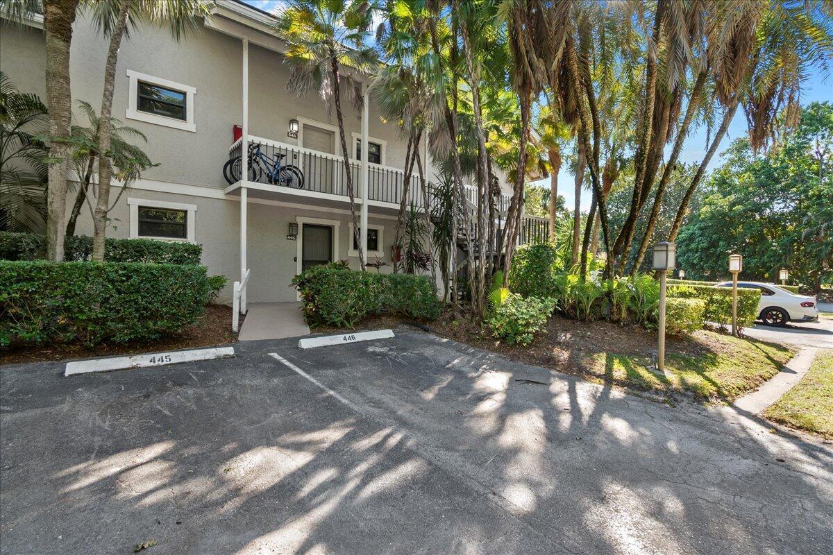A two-story apartment building exterior features a ground-level entrance and a second-floor balcony with bicycles — 11863 Wimbledon Circle # 446, Wellington FL 33414, WELLINGTON, FL