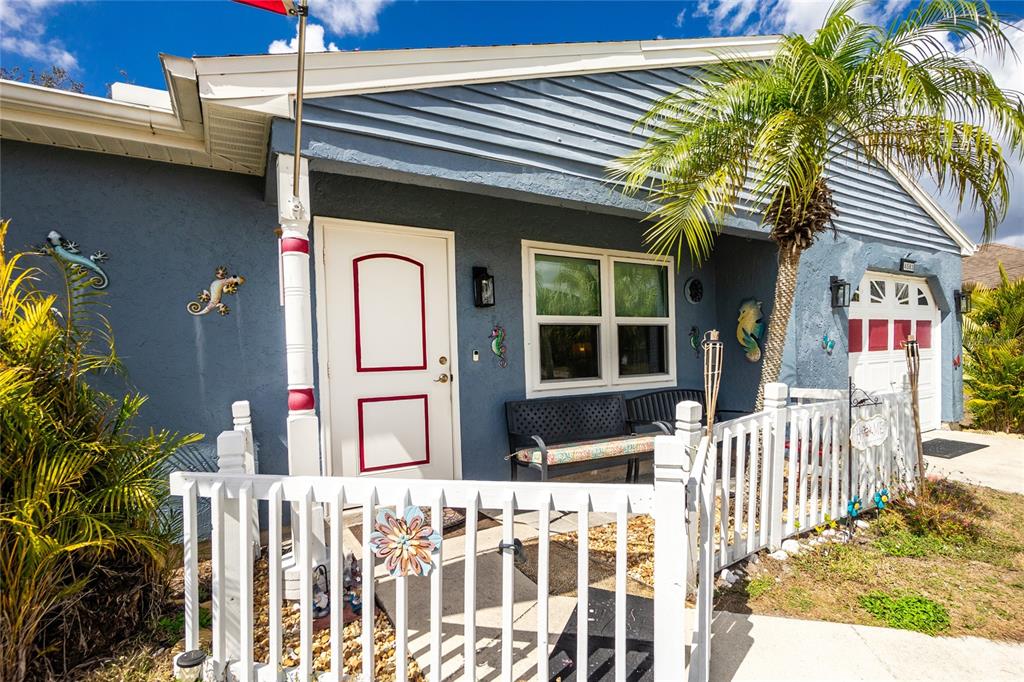 A blue house exterior features a white front door, a porch bench, and a white fence — 4583 S SALFORD BOULEVARD, NORTH PORT, FL