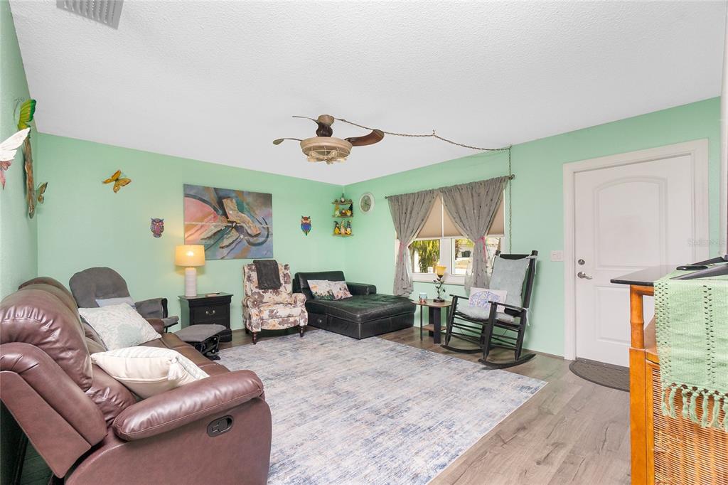 A living room with light green walls, a brown leather sofa, and a ceiling fan — 4583 S SALFORD BOULEVARD, NORTH PORT, FL
