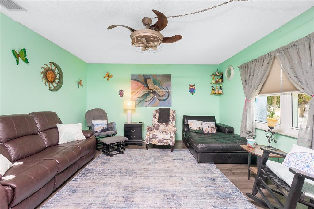 A living room features mint green walls, a brown leather sofa, and a ceiling fan — 4583 S SALFORD BOULEVARD, NORTH PORT, FL