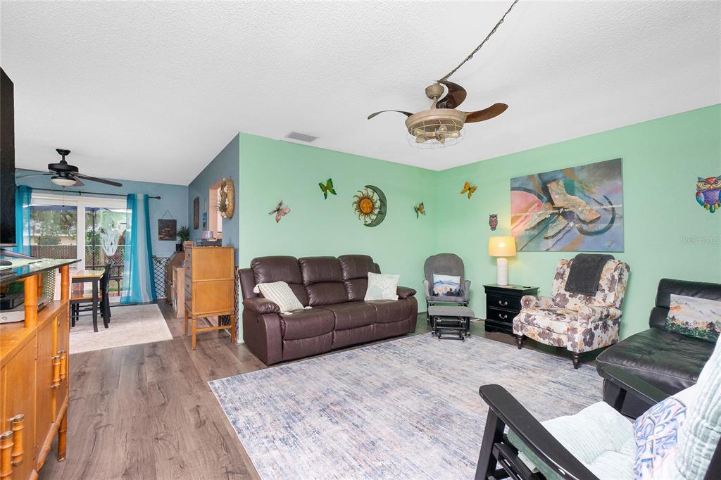 A living room features light green walls, wood-look flooring, a brown sofa, and a ceiling fan — 4583 S SALFORD BOULEVARD, NORTH PORT, FL