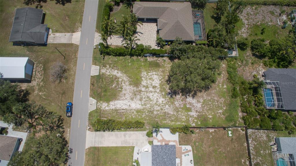 An aerial view shows a vacant residential lot situated between two houses along a paved road — 2450 ALAMANDER AVENUE, ENGLEWOOD, FL