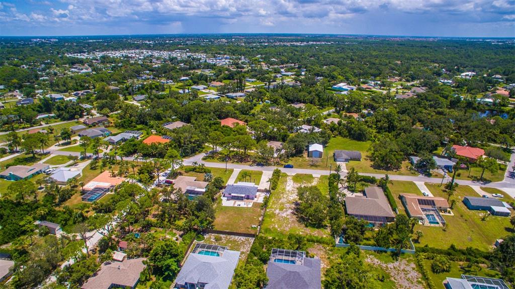 An aerial view shows a residential neighborhood with single-family homes, swimming pools, and lush vegetation — 2450 ALAMANDER AVENUE, ENGLEWOOD, FL