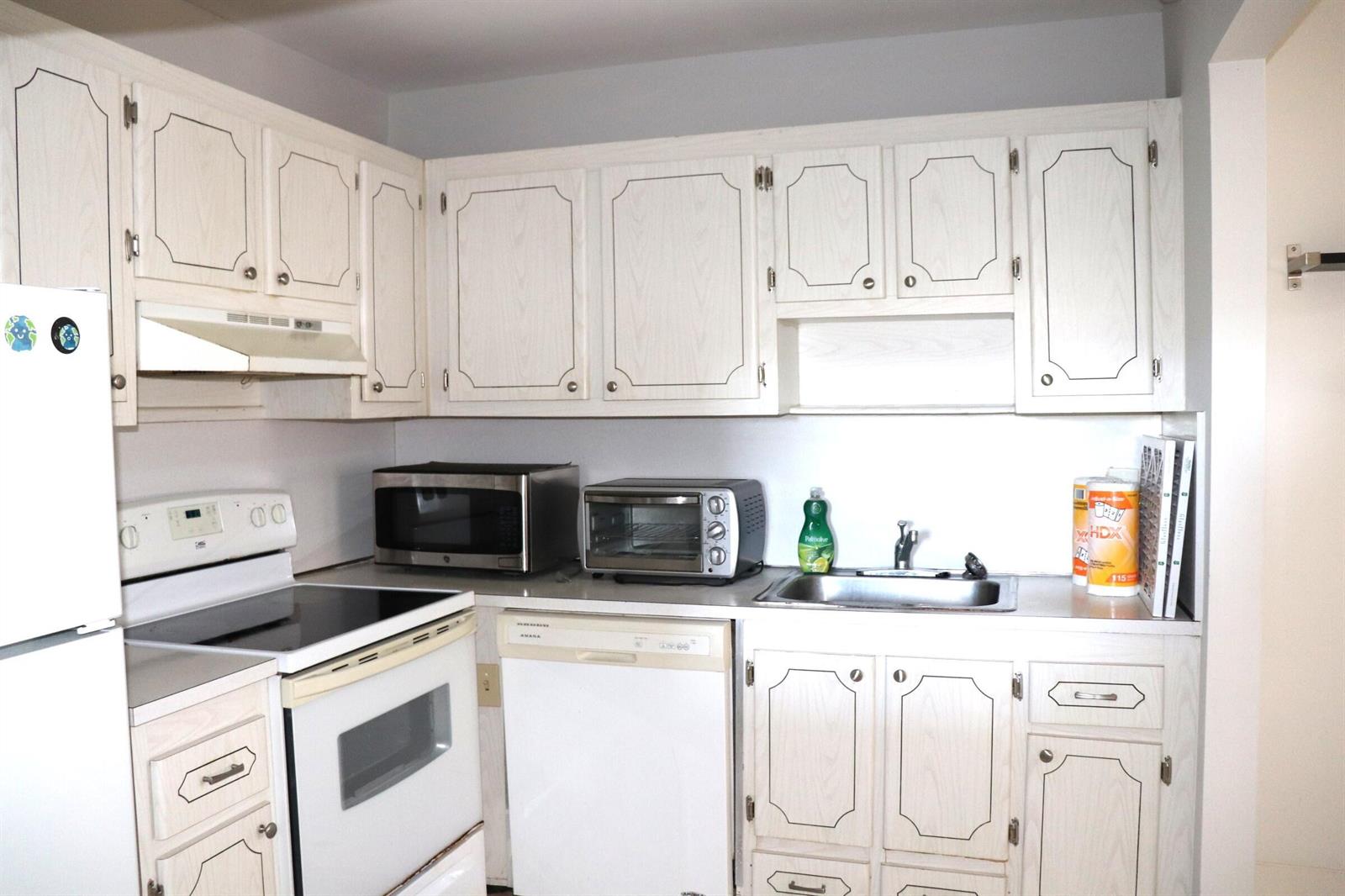 A kitchen featuring white cabinets with dark trim, white appliances, and a stainless steel sink — 79 Brittany # B, Delray Beach FL 33446, DELRAY BEACH, FL
