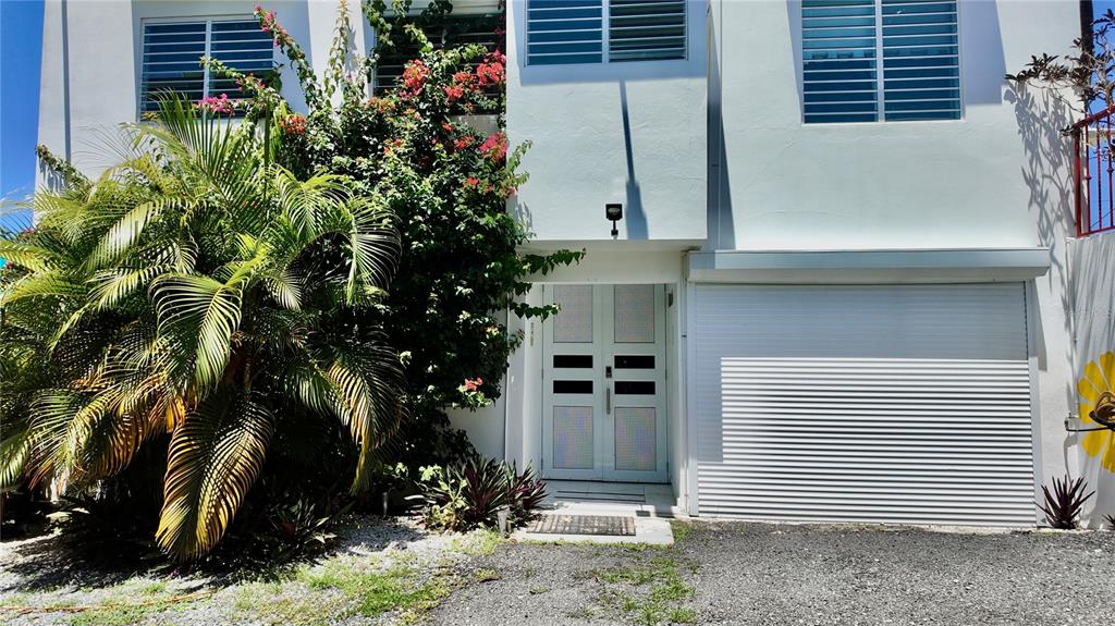 A white two-story building features a double front door, a roll-down garage door, and landscaping — 412 CARR EL COQUI, RINCON, PR