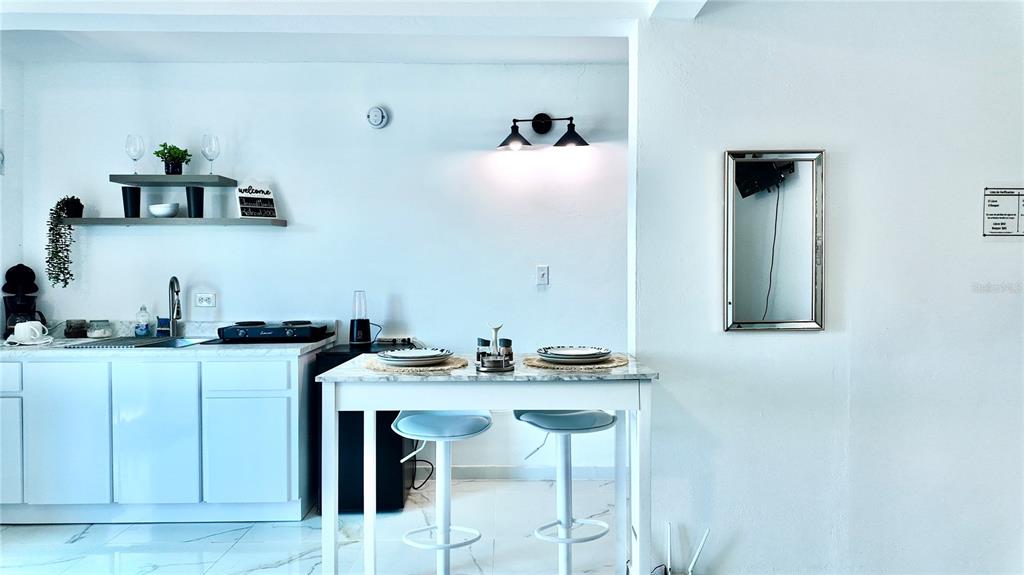 A small kitchen area features white cabinetry, a marble-topped dining table, and two stools — 412 CARR EL COQUI, RINCON, PR