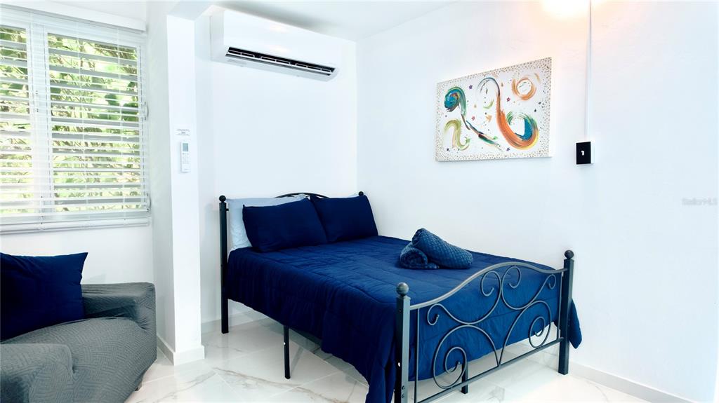 A bedroom features a dark blue bed, a gray armchair, and a wall-mounted air conditioner — 412 CARR EL COQUI, RINCON, PR