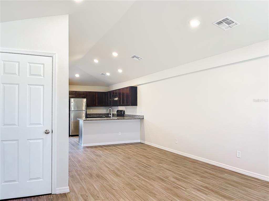 An open-concept kitchen with dark cabinets and granite countertops overlooks a spacious living area — 17053 NIXON AVENUE, PORT CHARLOTTE, FL