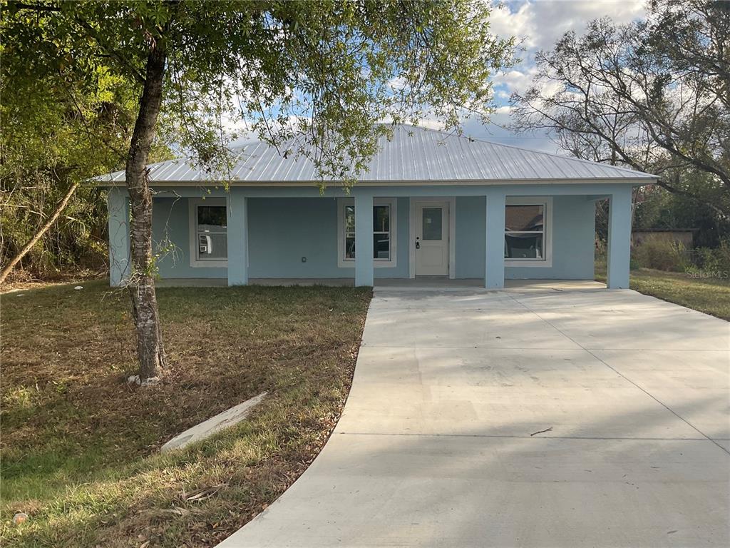 A light blue single-story house with a metal roof and a concrete driveway — 2432 NW 5TH STREET, OKEECHOBEE, FL