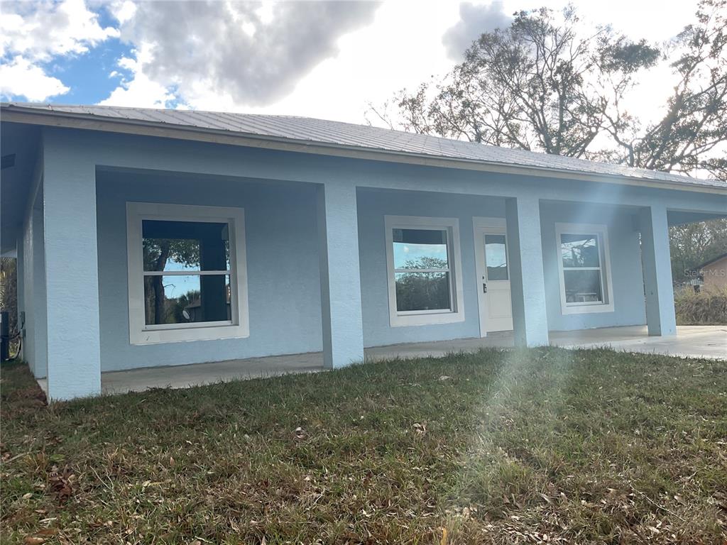 A light blue house with a covered front porch and a metal roof — 2432 NW 5TH STREET, OKEECHOBEE, FL