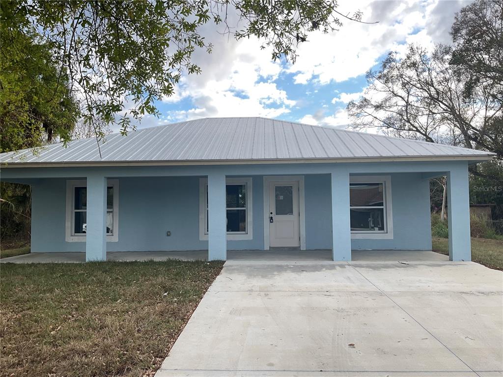 A light blue, single-story house with a metal roof and a covered front porch — 2432 NW 5TH STREET, OKEECHOBEE, FL