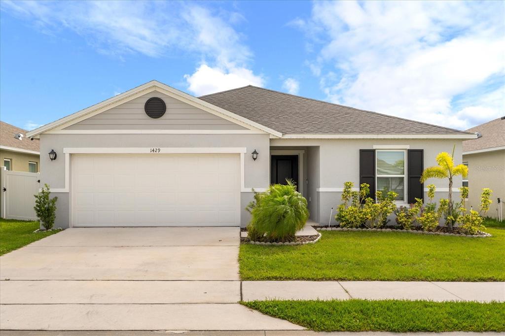 A single-story suburban house with a two-car garage, gray siding, and a landscaped front yard — 1429 MATTIE POINTE LANE, AUBURNDALE, FL