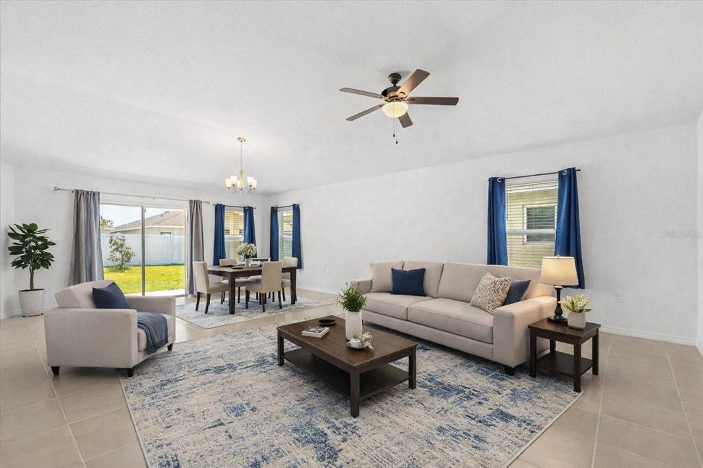 A living and dining room with tile floors, a ceiling fan, and blue curtains — 1429 MATTIE POINTE LANE, AUBURNDALE, FL