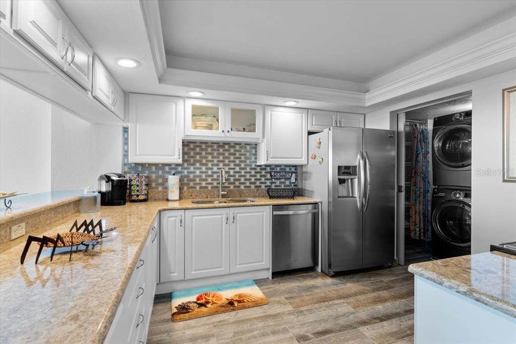 A kitchen features white cabinets, granite countertops, stainless steel appliances, and a tiled backsplash — 3855 S ATLANTIC AVENUE UNIT PH5, DAYTONA BEACH SHORES, FL