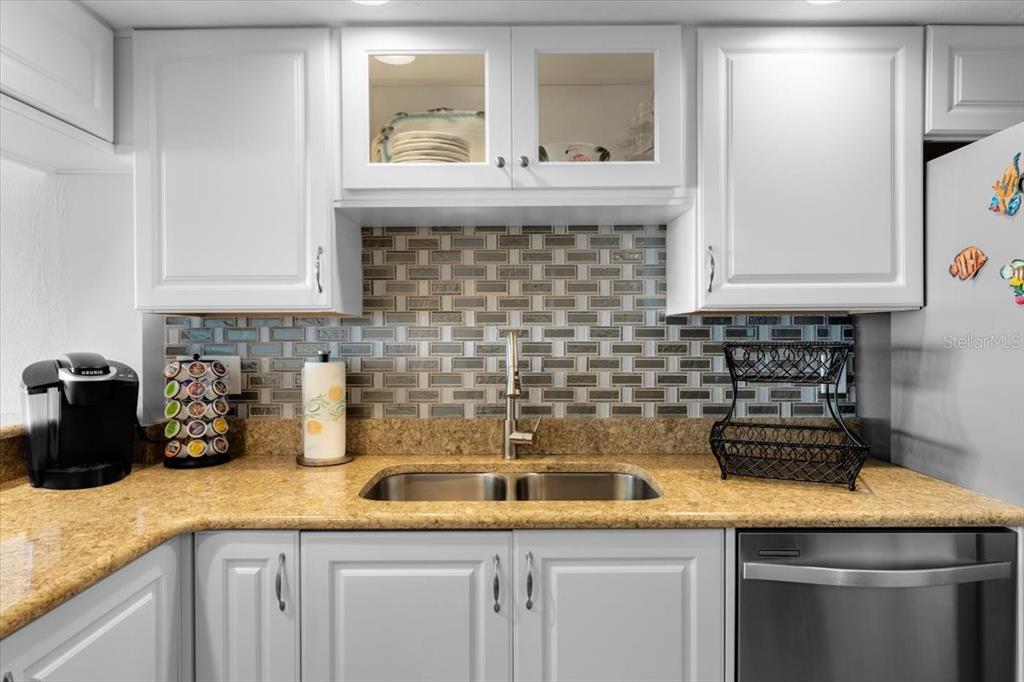 A kitchen features white cabinets, a tan granite countertop, a double sink, and tiled backsplash — 3855 S ATLANTIC AVENUE UNIT PH5, DAYTONA BEACH SHORES, FL