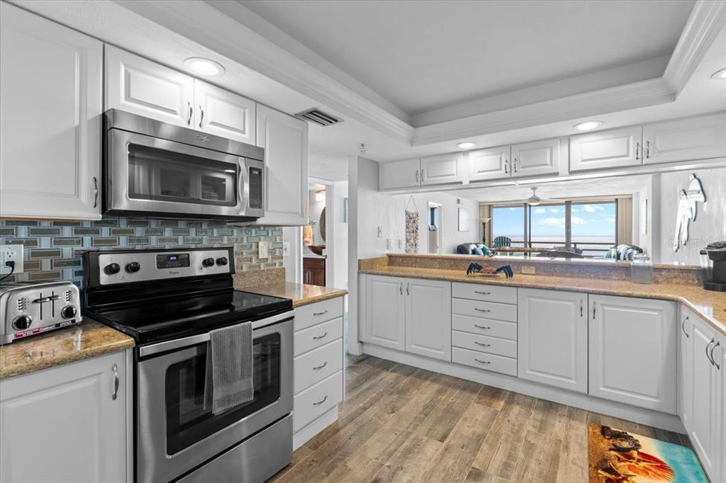 A kitchen with white cabinets, stainless steel appliances, and a view of the ocean — 3855 S ATLANTIC AVENUE UNIT PH5, DAYTONA BEACH SHORES, FL
